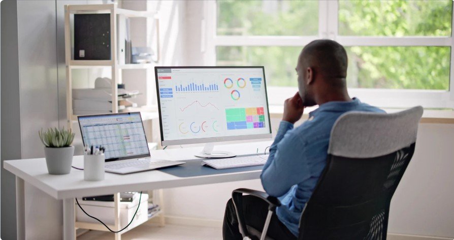 IT professional analyzing business data on multiple monitors in a modern office